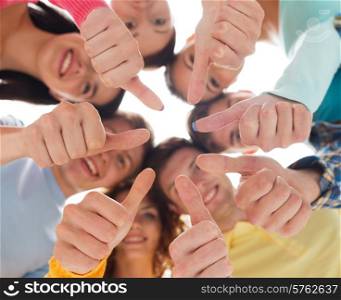 friendship, youth, gesture and people - group of smiling teenagers in a circle showing thumbs up