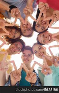 friendship, youth, gesture and people - group of smiling teenagers in circle showing victory sign