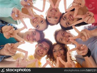 friendship, youth, gesture and people - group of smiling teenagers in circle showing victory sign