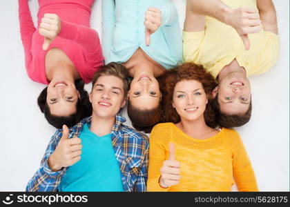 friendship, youth, gesture and people - group of smiling teenagers lying on floor and showing thumbs up