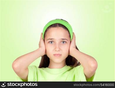 Frightened girl covering her ears isolated on a green background