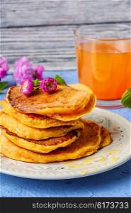 fritter pancakes with light dishes and glass of juice. pancakes with pumpkin
