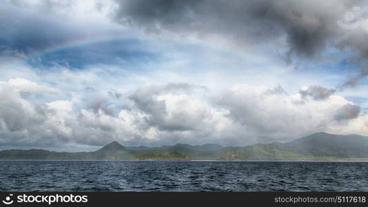 from a boat the rainbow from ocean and island in background