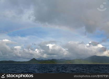 from a boat the rainbow from ocean and island in background