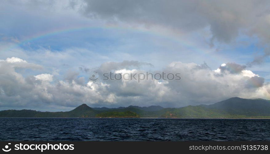 from a boat the rainbow from ocean and island in background