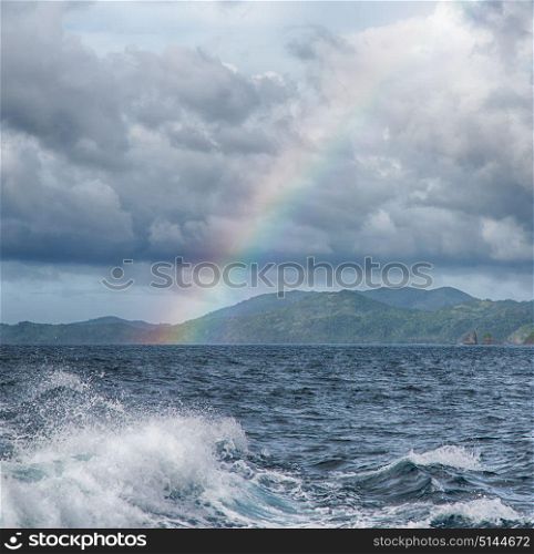 from a boat the rainbow from ocean and island in background
