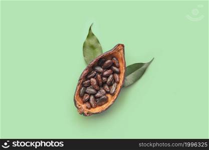 From above of half of organic cocoa pod with pile of peeled Theobroma cocoa beans place don green background. Cocoa pod filled with aromatic beans