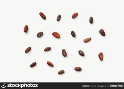 From above pile of scattered peeled aromatic cocoa beans of Theobroma cacao tree on white background. Scattered raw beans of cocoa