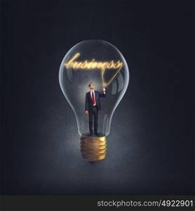 From inside of idea. Businessman inside of glass light bulb on dark background