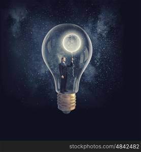 From inside of idea. Businessman inside of glass light bulb with moon balloon on dark background