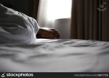 From sleeping woman in bed one sees foot under the blanket