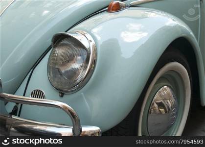 Front fender and headlight of blue vintage car detail closeup