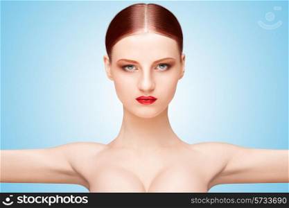 Front portrait of a nude girl with beautiful face and arms wide open on blue background.