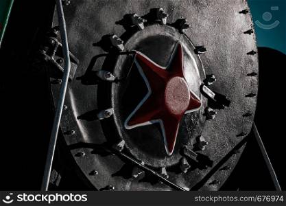 Front red star on black cabin of old soviet steam locomotive, close up, dramatic light
