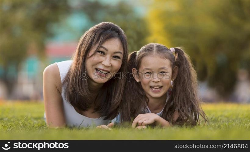 front view asian mother daughter staying grass together