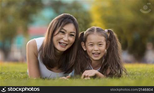 front view asian mother daughter staying grass together