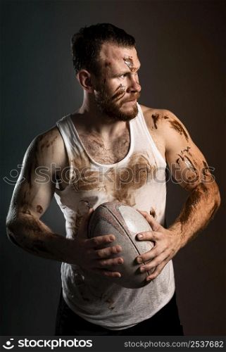 front view athletic dirty male rugby player holding ball