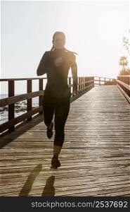 front view athletic woman jogging by beach with copy space