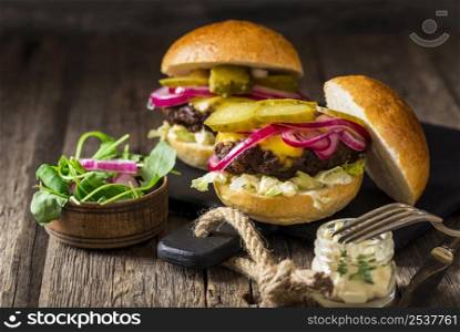 front view beef burgers with pickles red onions cutting board