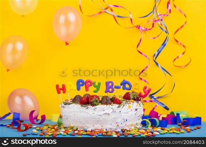 front view birthday cake surrounded by party elements