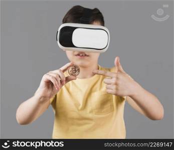 front view boy holding bitcoin while wearing virtual reality headset