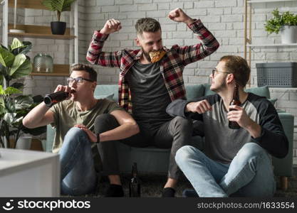 front view cheerful male friends having pizza watching sports tv