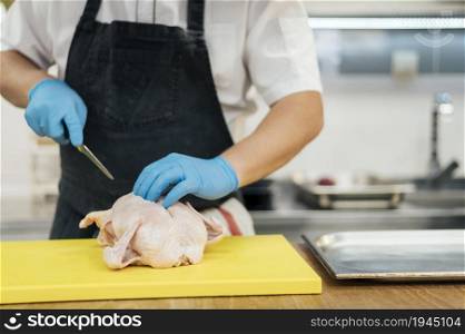 front view chef with gloves cutting chicken. High resolution photo. front view chef with gloves cutting chicken. High quality photo