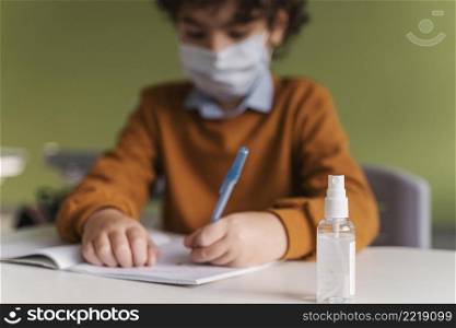 front view child with medical mask class with bottle hand sanitizer desk