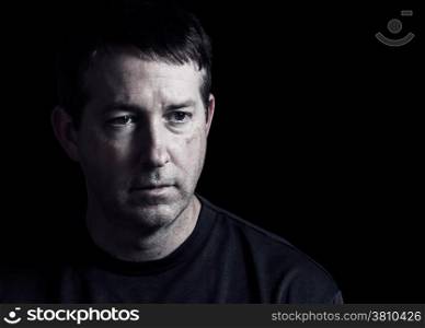 Front view close up of mature man showing negative emotions with dark background