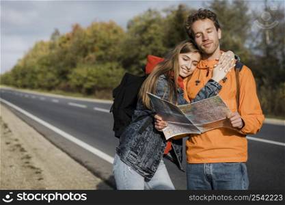 front view couple holding map sitting along road