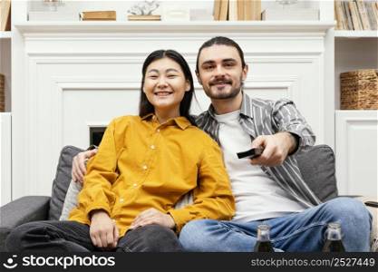 front view couple sitting couch watching tv