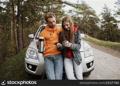 front view couple together road trip enjoying hot beverage