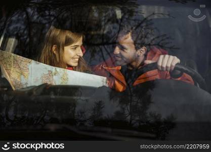 front view couple with map inside car going road trip