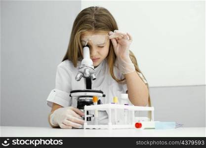 front view curious young girl scientist using microscope