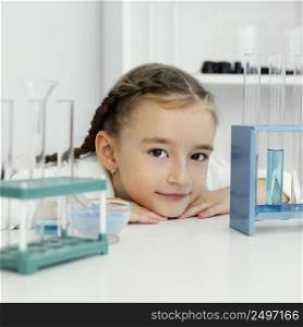 front view cute young girl scientist with test tubes