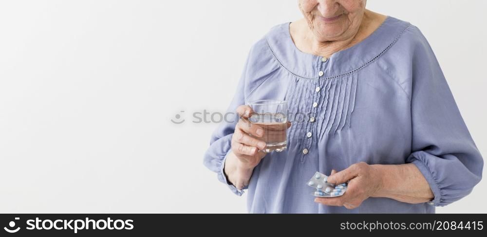 front view elder woman taking her pills with copy space