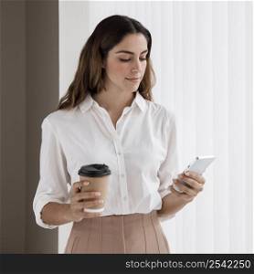 front view elegant businesswoman holding coffee cup smartphone