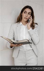 front view elegant businesswoman with agenda talking phone