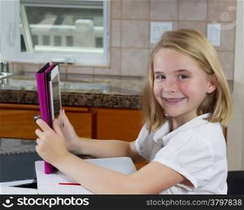Front view, facing forward, of pretty little girl doing her homework while in the kitchen
