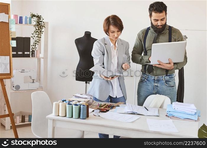 front view fashion designers working atelier with laptop