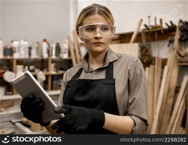 front view female carpenter with safety glasses holding tablet