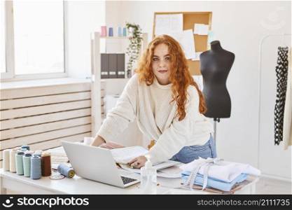 front view female fashion designer working atelier with laptop