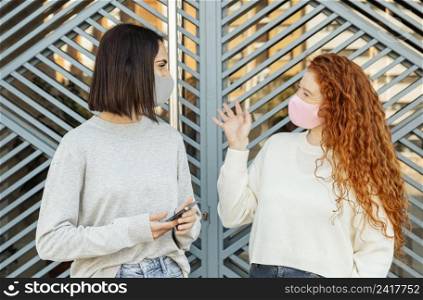 front view female friends with face masks outdoors conversing