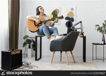 front view female musician home playing acoustic guitar singing