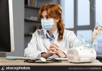 front view female physician her desk with medical mask looking computer