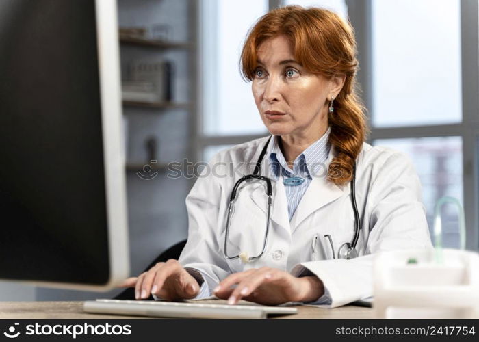 front view female physician looking up stuff computer desk