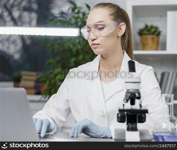 front view female researcher laboratory with safety glasses microscope