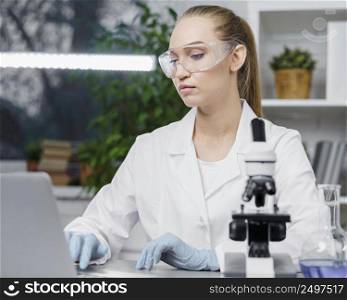 front view female researcher laboratory with safety glasses microscope