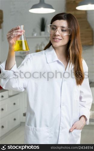 front view female scientist with safety glasses holding test tube