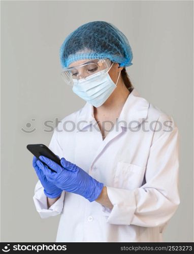 front view female scientist with safety glasses medical mask holding smartphone